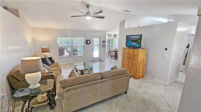 Tiled living room with vaulted ceiling and ceiling fan