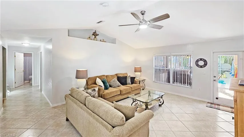 Living room featuring light tile patterned flooring, ceiling fan, and vaulted ceiling