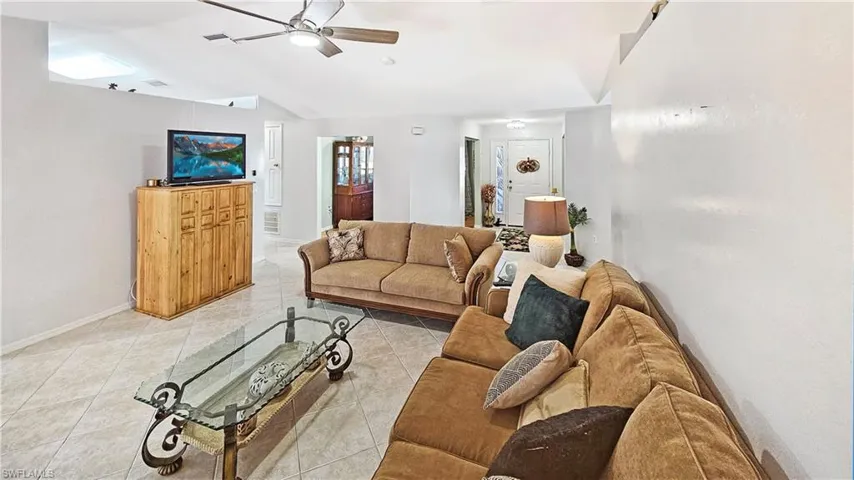 Tiled living room featuring ceiling fan and lofted ceiling