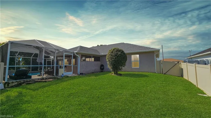 Back of house featuring a pool, a lanai, and a lawn