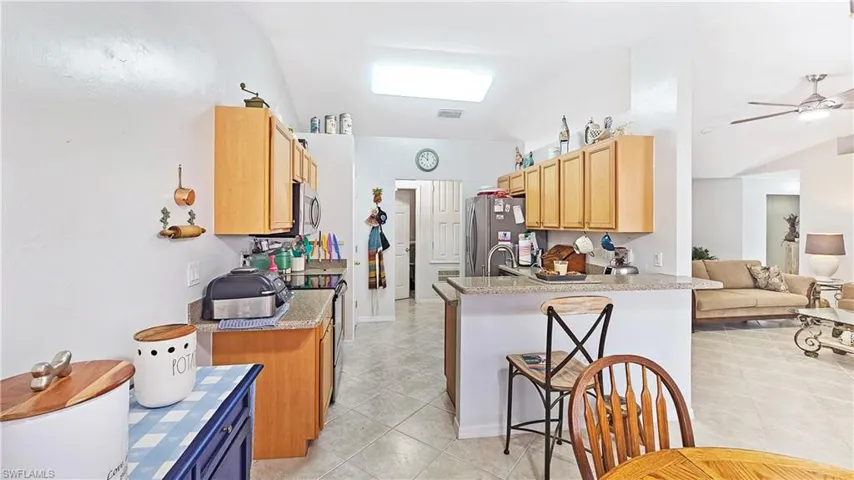 Kitchen featuring sink, light tile patterned floors, ceiling fan, kitchen peninsula, and stainless steel appliances
