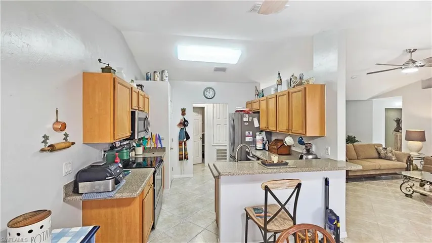 Kitchen with a breakfast bar, sink, ceiling fan, kitchen peninsula, and stainless steel appliances