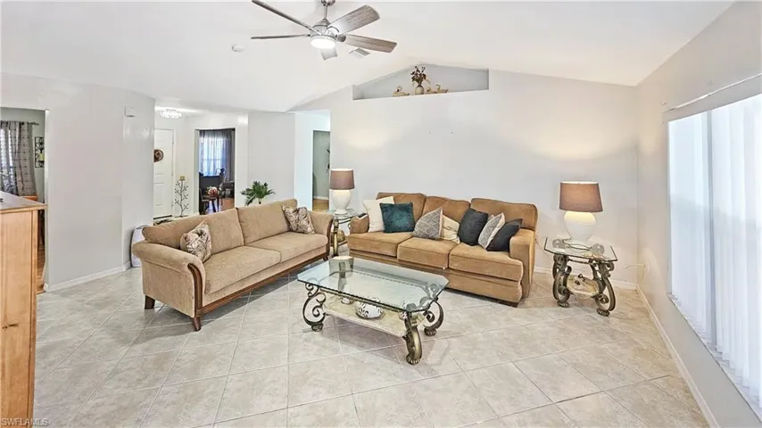 Tiled living room with ceiling fan and lofted ceiling