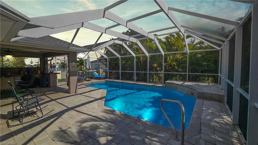 View of pool with a patio area and glass enclosure