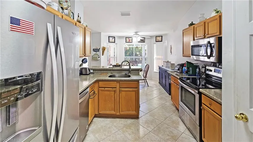 Kitchen with sink, light tile patterned floors, ceiling fan, appliances with stainless steel finishes, and kitchen peninsula