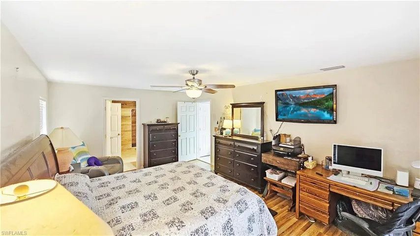 Bedroom with hardwood / wood-style flooring, connected bathroom, ceiling fan, and a closet