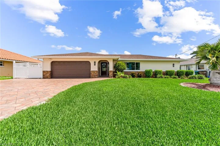 View of front of home with a garage and a pavered driveway