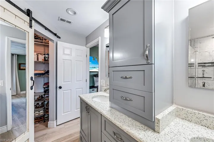 Master en-suite Bathroom featuring walk in closet, tile flooring, and dual vanity