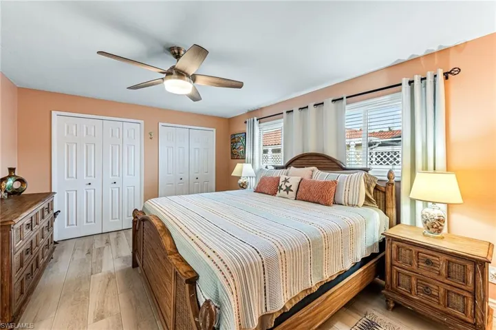 Bedroom with multiple closets, light tile flooring, and ceiling fan