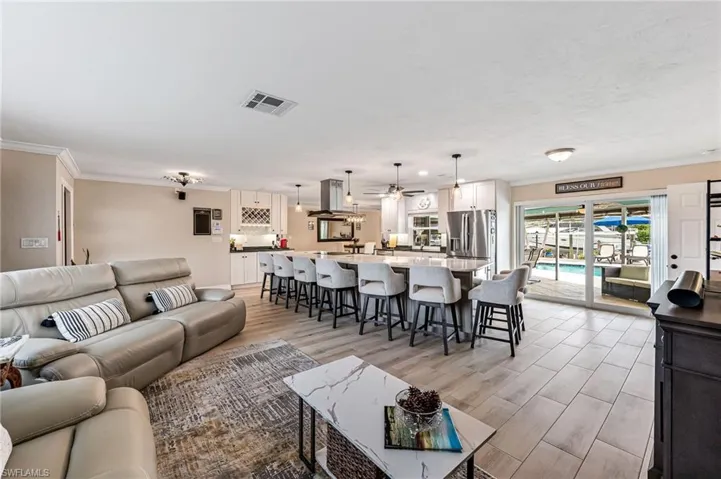 Living room featuring crown molding, large island, light tile flooring