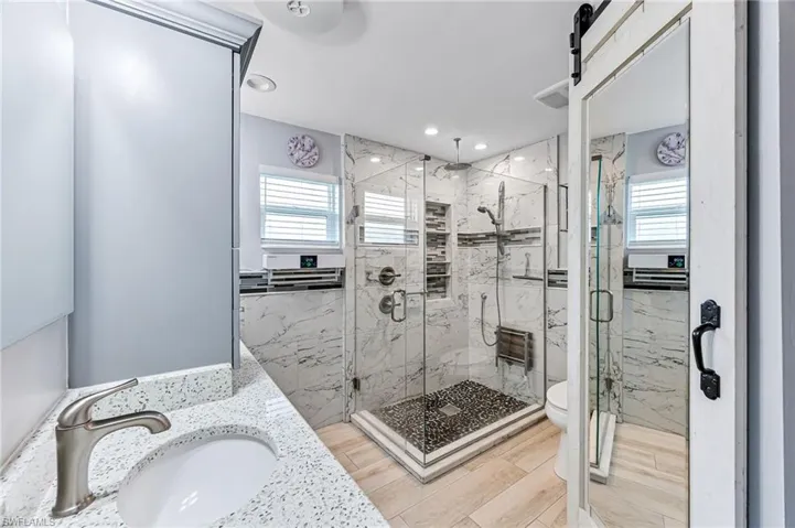 Master en-suite bathroom with plenty of natural light, tile floors, an enclosed shower, and toilet
