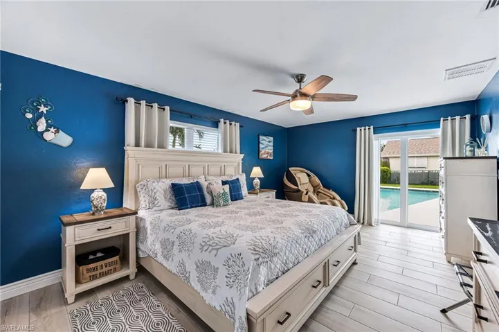 Bedroom featuring light tile floors, multiple windows, ceiling fan, and access to exterior