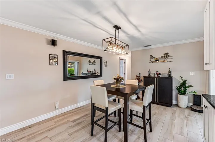 Dining room with light tile floors, crown molding, and a chandelier