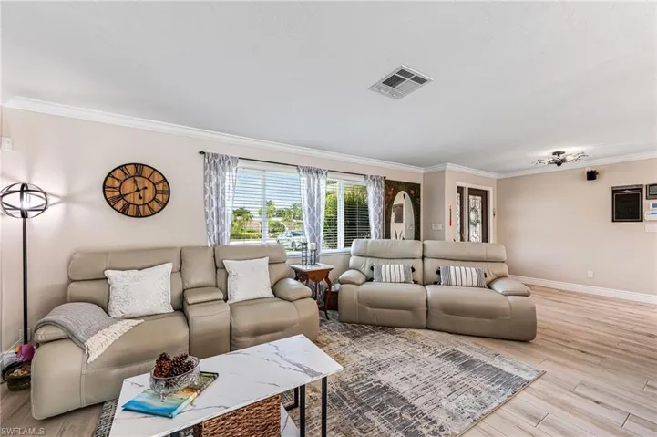 Living room with ornamental molding and light tile flooring