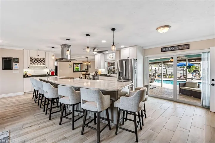Kitchen featuring gray cabinetry, marble counter, stainless steel fridge, pendant lighting, and a spacious island