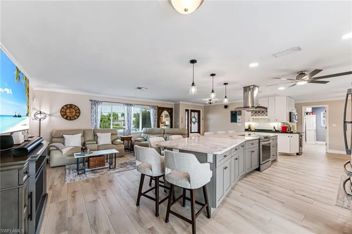 Kitchen featuring light tile flooring, stainless steel range with electric stovetop, gray cabinets, marble countertop, and island range hood