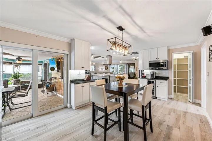 Dining area featuring ornamental molding, light tile flooring, pantry/ storage, coffee and wine bar, wine cooler