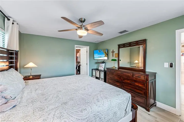 Master bedroom featuring light tile floors, a walk in closet, and ceiling fan
