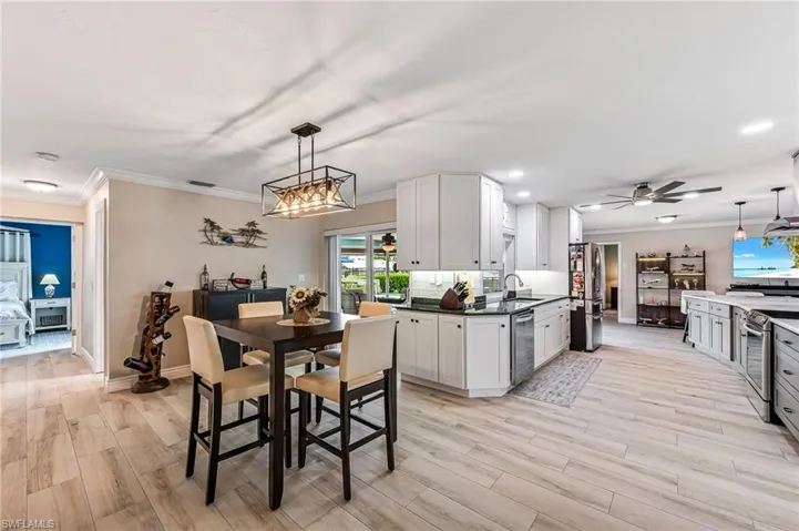 Kitchen featuring ceiling fan, white cabinetry, sink, and pendant lighting