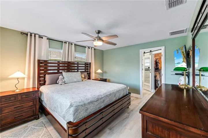 Master bedroom featuring light tile flooring, ensuite bath, a walk in closet, and ceiling fan