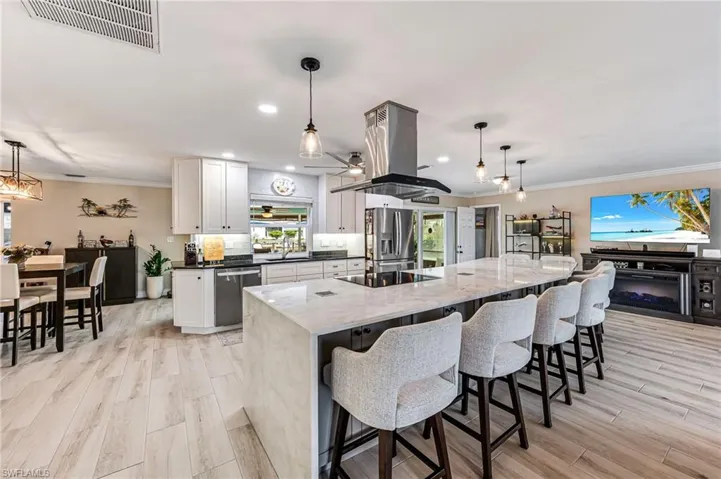 Kitchen with white cabinetry, gray cabinetry, large island, stainless steel appliances, and island exhaust hood