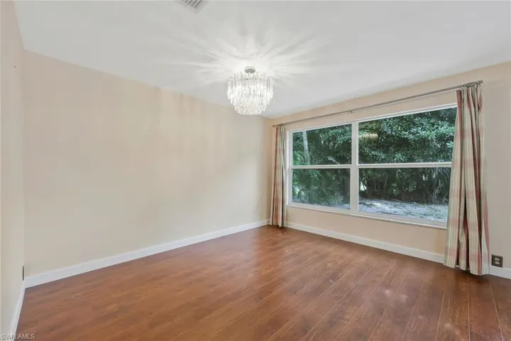Guest bedroom with dark wood-style flooring and suspended lighting