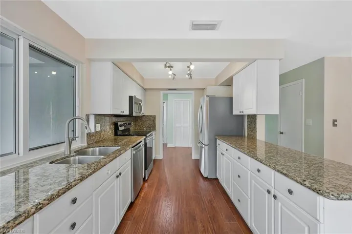 Kitchen featuring dark stone countertops, backsplash, a peninsula, and stainless steel appliances