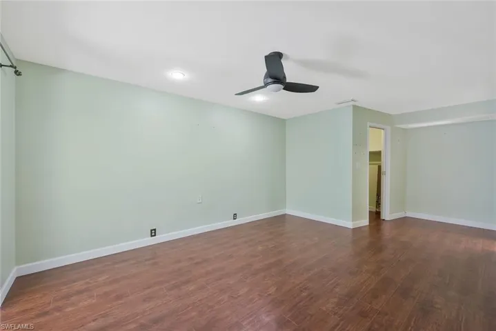 Primary bedroom with dark wood-style floors and a ceiling fan
