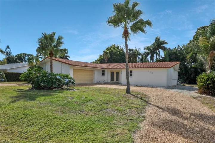Single story home with circular driveway featuring a garage, french doors, stucco siding, and a tiled roof