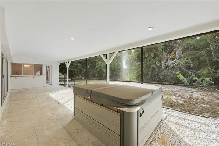 Unfurnished sunroom featuring a hot tub and a patio area
