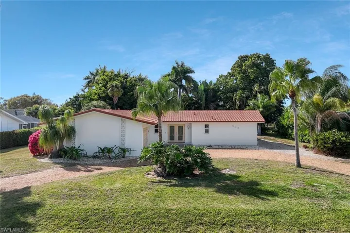 View of front of property featuring a front lawn, stucco siding, french doors, and a tile roof