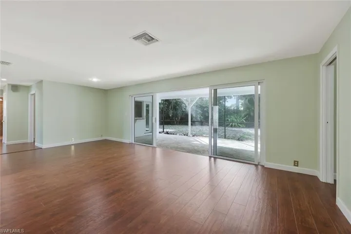 Living Room featuring baseboards and dark wood-style flooring and sliders to screened lanai