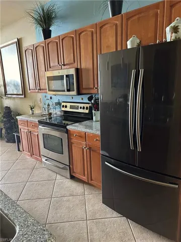 Kitchen featuring stainless steel appliances, light stone countertops, and wood finish cabinets