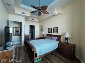 Bedroom with a tray ceiling, dark wood finished floors, and ceiling fan