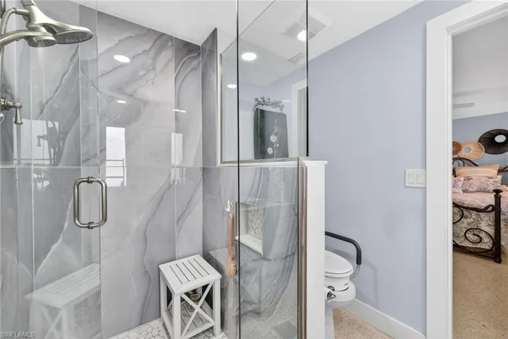 Primary Bathroom with a marble finish shower and speckle patterned floor