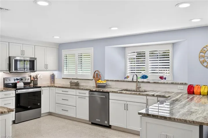 Kitchen featuring stainless steel appliances, light stone counters, tasteful backsplash, recessed lighting, and white cabinets
