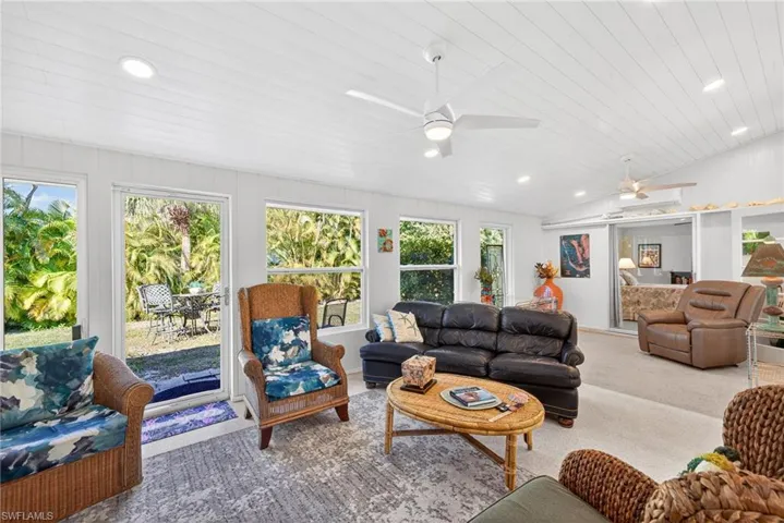 Carpeted living room with a ceiling fan, recessed lighting, and a vaulted wooden ceiling