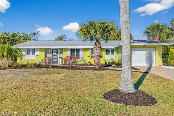 Ranch-style home with a garage, concrete driveway, and a front lawn