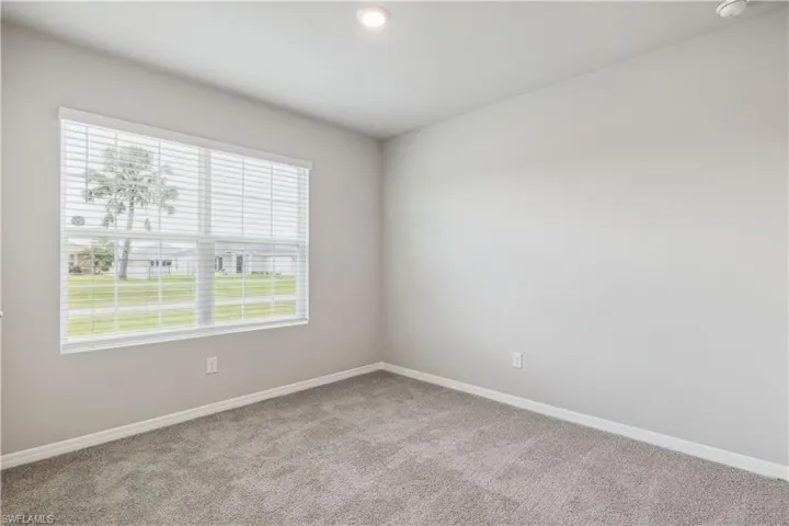 Empty room with carpet floors and an inviting chandelier