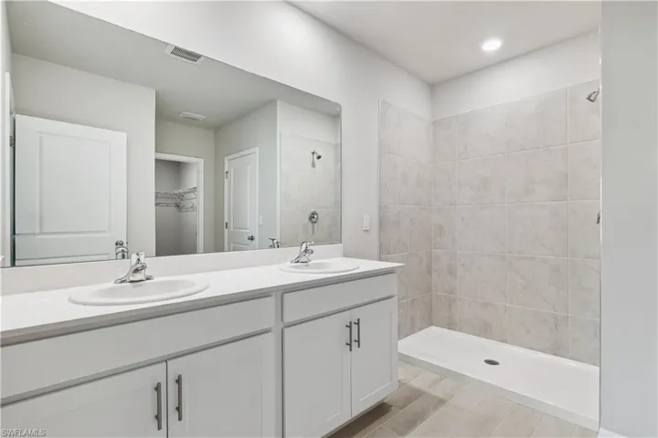 Bathroom with double vanity, a tile shower, and hardwood / wood-style floors