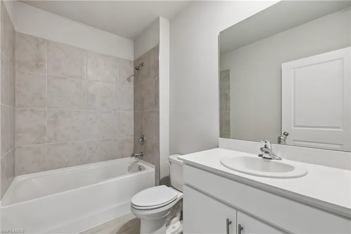 Full bathroom featuring vanity, tiled shower / bath combo, and toilet