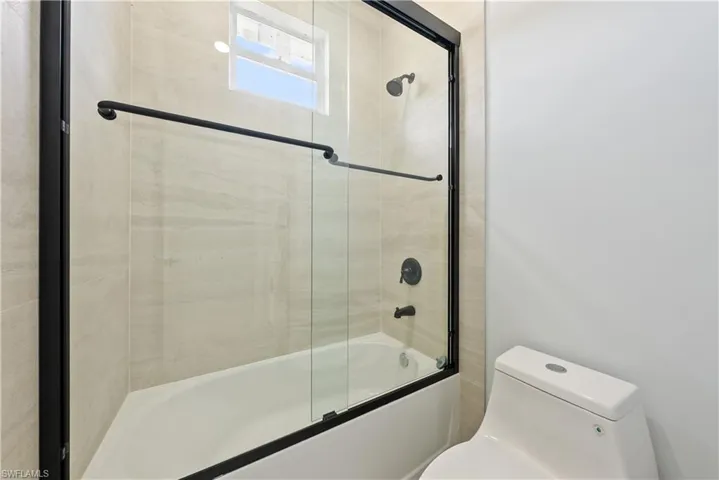 Full bathroom featuring combined bath / shower with glass door and toilet