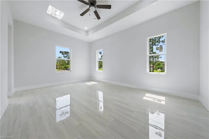 Empty room featuring a ceiling fan, a tray ceiling, and recessed lighting