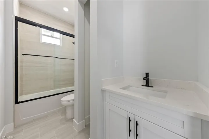 Bathroom with shower / bath combination with glass door, vanity, and recessed lighting