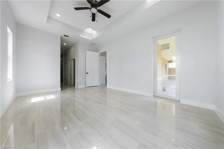 Empty room with a ceiling fan, a raised ceiling, and recessed lighting