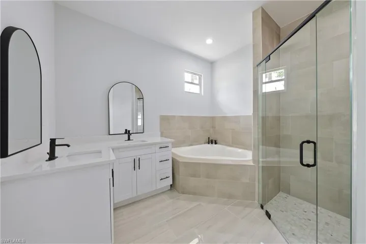 Bathroom with a bath, double vanity, a stall shower, tile patterned flooring, and recessed lighting