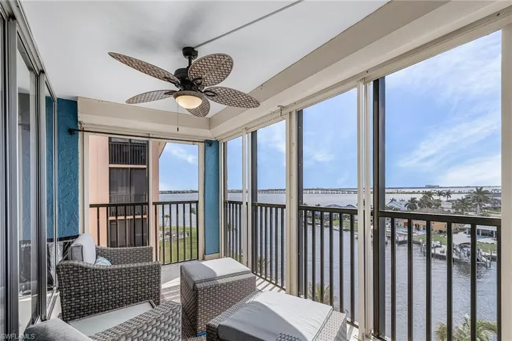 Sunroom with ceiling fan, a water view, and a balcony