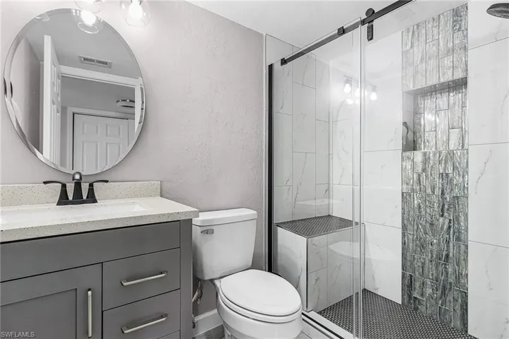 Full bath featuring a textured wall, vanity, and a stall shower