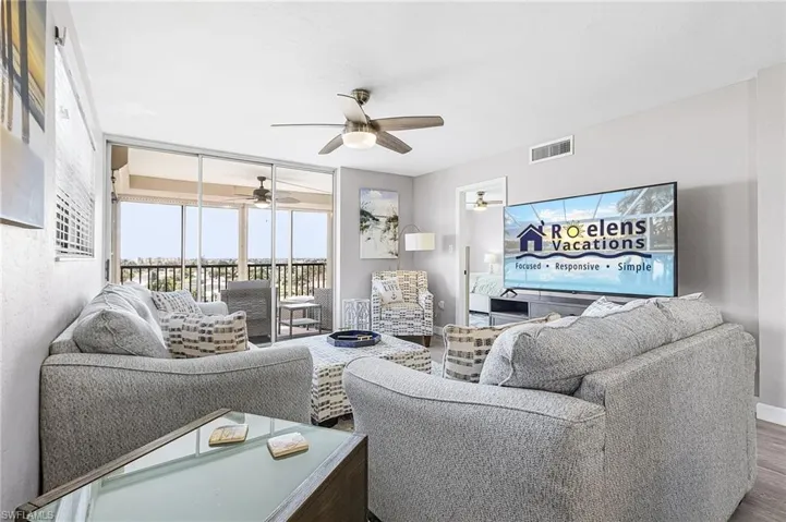 Living room featuring wood finished floors, expansive windows, and a ceiling fan