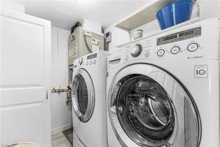 Laundry room with washing machine and dryer and light wood-style flooring